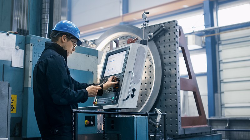 Fabrikarbeiter programmiert eine Maschine mit einem Tablet-Computer.