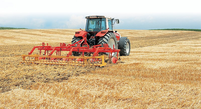 Traktor mit Pflugmaschine auf dem gemähten Getreidefeld
