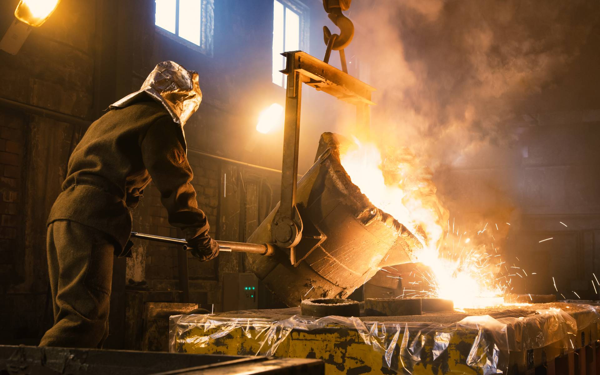 Arbeiter, der die Metallschmelze in Öfen steuert. Das flüssige Metall wird in Formen gegossen.